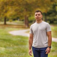 Nick Corman, a kidney transplant recipient, stands in a park, looking satisfied.