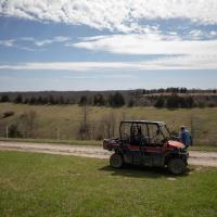 Howard Galbreath exits a farm vehicle on a road near his farm, photographed at a wide angle