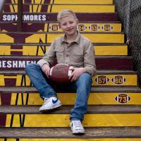 William Dean sitting on yellow steps, posing with a football