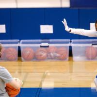 A photo of Amber, wearing a mask and gloves, coaching a practice.