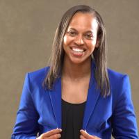 A portrait photo of Amber, dressed in a black blouse and a blue blazer, smiling at the camera.