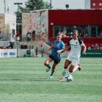 Arin runs after an opponent with the ball during a soccer game.