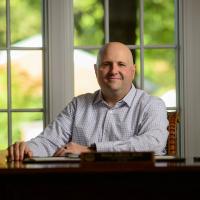 Dr. Adkins sits behind a desk at his home office.