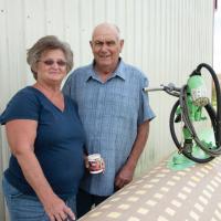 Charlotte and her husband pose together for a photo outside of their barn.