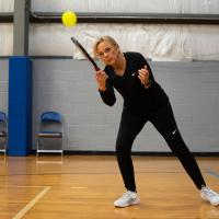 Donna leans into a swing to hit the ball back during a pickleball game.