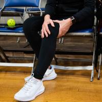 Donna holds her knee while sitting in a chair at a pickleball game.