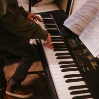 Evan is standing and playing on his piano keyboard.