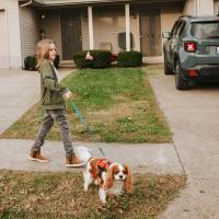 Evan is outside, taking his small dog on a walk.