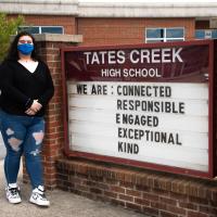 Faith wears her blue face mask and stands in front of her high school's message board. Tates Creek High School. \