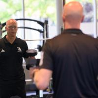 A.W. watches himself in the mirror as he lifts weights in the gym.