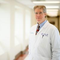 A photo of Dr. Selby standing in the hallway of the hospital as he smiles for the camera.