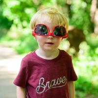 Jeremiah poses for the camera while wearing a pair of oversized sunglasses that are upside down on his face.