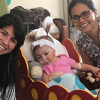 A photo of Dr. Shenoi and a member of Kailey’s care team smiling as they pose for a picture with baby Kailey.