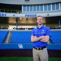 A photo of Matt standing on the field with his arms crossed as he looks into the camera.