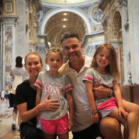 Matthew Mitchell and his wife and two daughters smile for a family photo in an ornate cathedral.