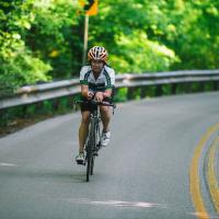 Patty bikes down a road outside.