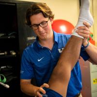 Peter helps stretch his student's knee and leg.