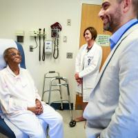 Priscilla smiles at her cardiologist and another doctor in an examination room.