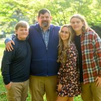 A photo of Ronald with his arms around his children as they pose together outside.