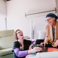 Sarah participates in music therapy from her hospital bed and laughs with her music therapist.