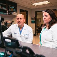 Dr. O’Donnell and his assistant sit and analyze information on a desktop computer.