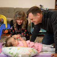 Gavin and Karla smile as they play with Wylie on the floor.