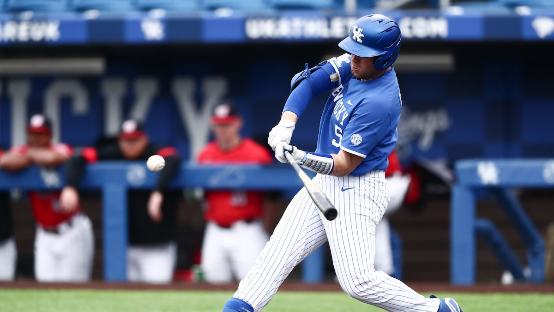 An action shot of T.J. about to hit a baseball during a game.