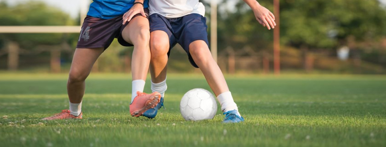 Two soccer players compete for the ball.