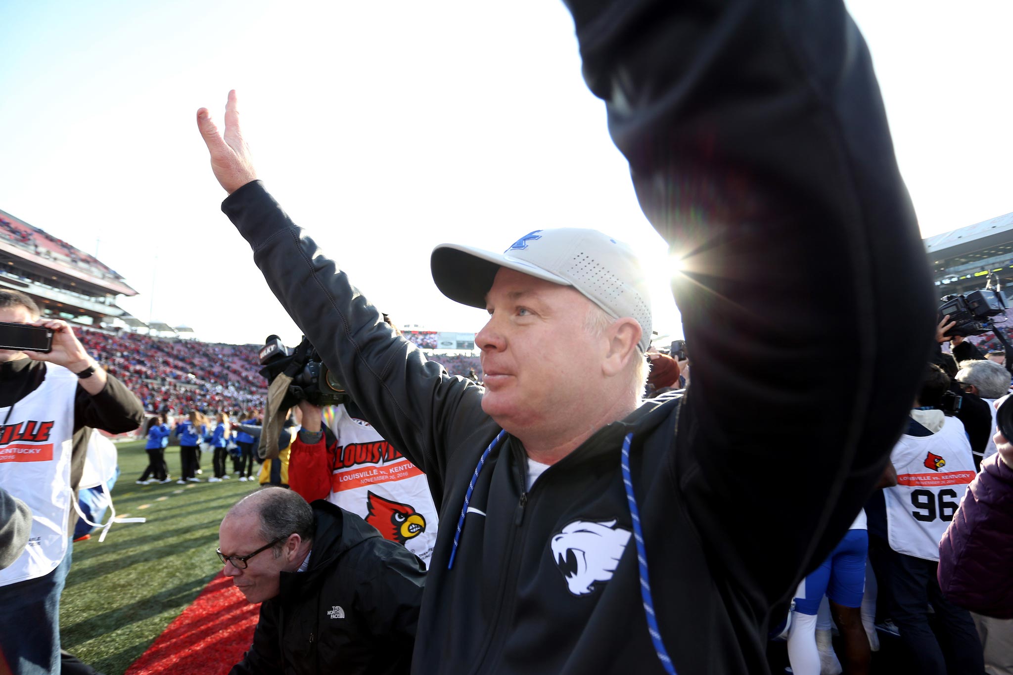 Coach Stoops raises his hands into the air during a football game while watching his players.