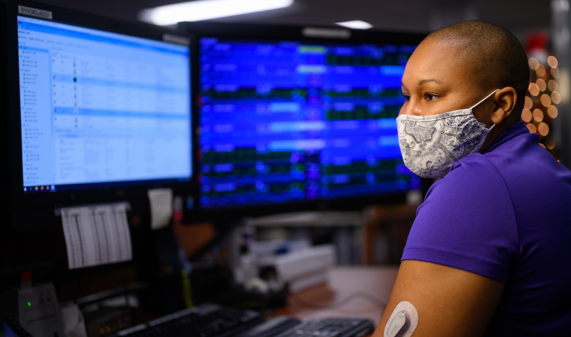 An over-the-shoulder shot of Whitley wearing a face mask and looking at a computer screen.