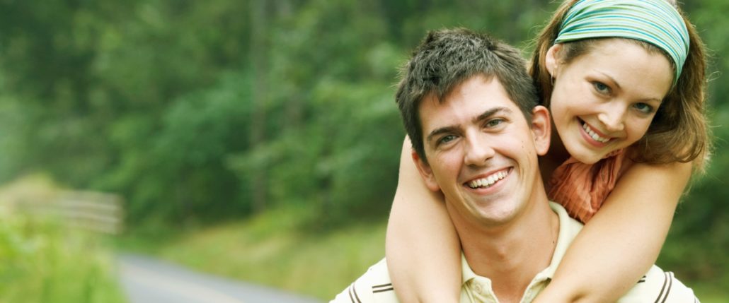 Women standing behind a man in warm embrace